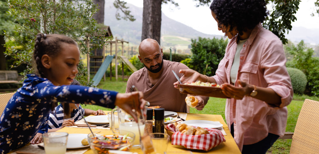 family eating dinner outside with garden in background